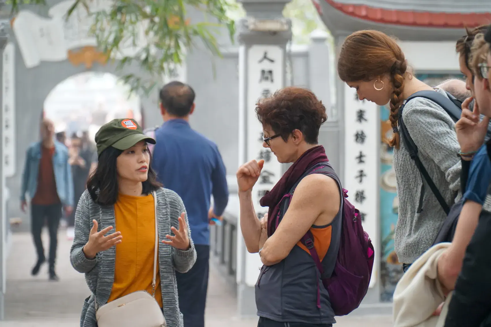 A Hanoi guide talking with travellers on a quiet Old Quarter street at golden hour.