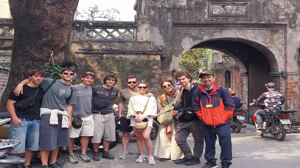 Guests Mario and Cesar with guide Luis visiting O Quan Chuong Gate during a Hanoi free walking tour