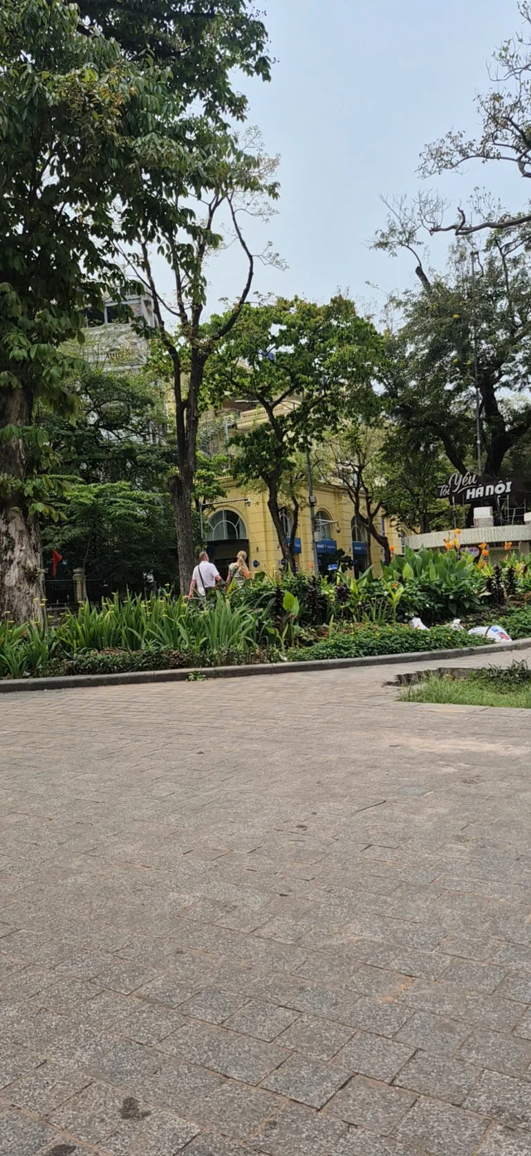 Garden path and yellow colonial building near Hoan Kiem Lake in Hanoi.