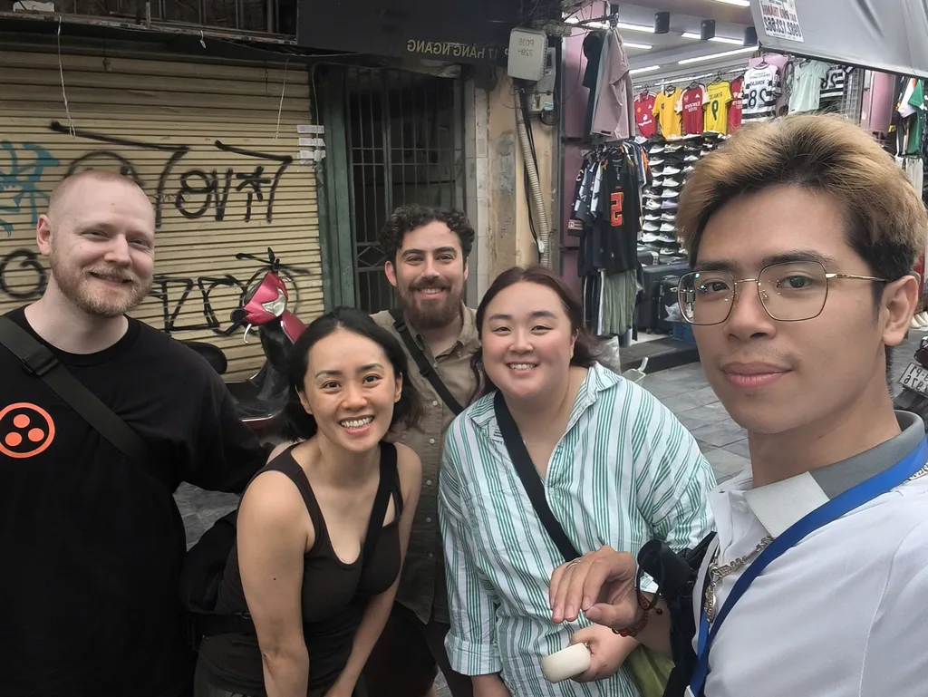 Guide and guests pausing on a narrow Hanoi street during a food walk.