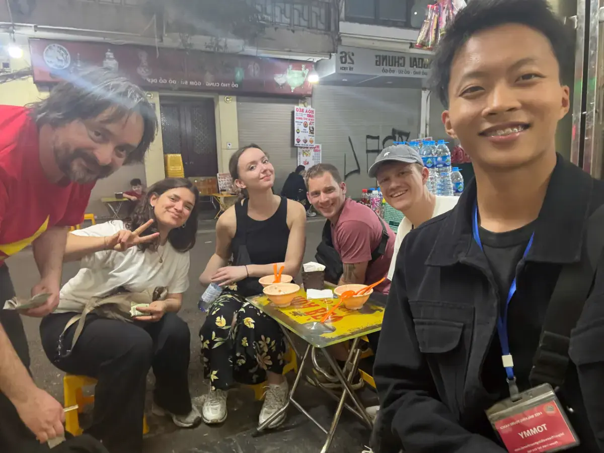 British travellers enjoying authentic Hanoi street food tour at night with local guide Tommy in the Old Quarter.