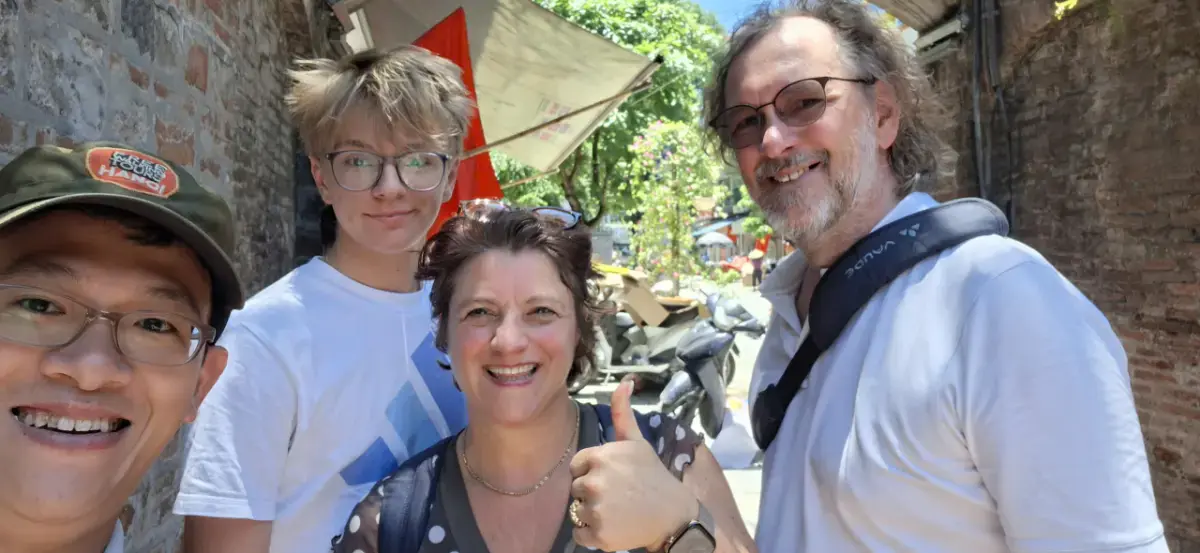 German traveller Richard from Munich with guide Hans exploring Phung Hung Mural Street and Dong Xuan Market in Hanoi Old Quarter.